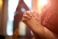 Woman hand holding rosary against cross and praying to God at church Royalty Free Stock Photo