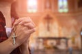 Woman hand holding rosary against cross and praying to God at church Royalty Free Stock Photo