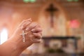 Woman hand holding rosary against cross and praying to God at church Royalty Free Stock Photo