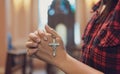 Woman hand holding rosary against cross and praying to God at church Royalty Free Stock Photo