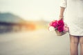 Woman hand holding rose flower hiding behind back side rear view to surprise couple on valentine`s day. Beauty woman giving