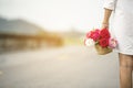 Woman hand holding rose flower hiding behind back side rear view to surprise couple on valentine`s day. Beauty woman giving