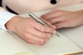 Woman hand holding silver pen ready to make note in opened notebook