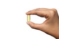 Woman hand holding single yellow Cod Liver Oil capsule on white background Royalty Free Stock Photo