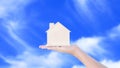 Woman hand holding small home model wooden with cloud blue sky background. Family life and Business real estate concept,Eco house Royalty Free Stock Photo