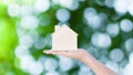 Woman hand holding small home model wooden with nature green bokeh abstract background. Family life and Business real estate Royalty Free Stock Photo