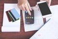 Woman hand holding smart phone calculating her monthly expenses with credit card,saving account book, deadline calendar concept fo Royalty Free Stock Photo