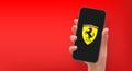 Woman hand holding the smartphone with logo Ferrari, vector editorial illustration