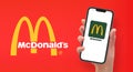 Woman hand holding the smartphone with logo McDonald`s, advertising wallpaper, Vector editorial illustration