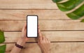 Woman hand holding a smartphone and pressing blank screen on wood table, take your advertising. Technology for communication.