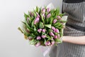 Woman hand holding soft lilac tulips flowers on white background. bouquet decorated with kraft paper Royalty Free Stock Photo