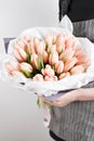 Woman hand holding soft pink tulips flowers on white background. bouquet decorated with kraft paper Royalty Free Stock Photo