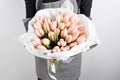 Woman hand holding soft pink tulips flowers on white background. bouquet decorated with kraft paper Royalty Free Stock Photo