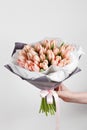 Woman hand holding soft pink tulips flowers on white background. bouquet decorated with kraft paper Royalty Free Stock Photo