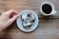 Woman hand holding a source with piece of chocolate cake. Cup of coffee and handmade brownie with cherries on a white plate Royalty Free Stock Photo