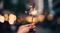 Woman hand holding sparkler on bokeh background. New Year and Christmas concept