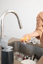 Woman Hand holding sponge with soap foam over sink with dirty glasses and dishes inside Royalty Free Stock Photo