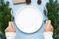 woman hand holding spoon and fork over Empty plate with Christmas decoration, preparation for Happy New Year and Xmas Royalty Free Stock Photo