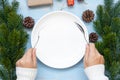 Woman hand holding spoon and fork over Empty plate with Christmas decoration, preparation for Happy New Year and Xmas Royalty Free Stock Photo