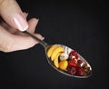 Woman hand holding spoon with fruits on isolate black diet concept photo closeup Royalty Free Stock Photo