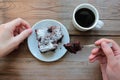 Woman hand holding a spoon with piece of chocolate cake. Cup of coffee and handmade brownie with cherries on a white plate Royalty Free Stock Photo