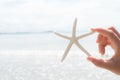 Woman hand holding starfish over sea and Sandy beach Royalty Free Stock Photo