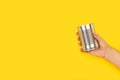 Woman hand holding a tin can on a yellow background Royalty Free Stock Photo