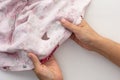 Woman hand holding torn cloth seamy side showing hole on the white background