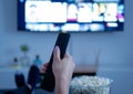 Woman hand holding tv remote with popcorn at home Royalty Free Stock Photo