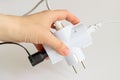 Woman hand holding white electric splitter with tree plugs socketed into it on a white background. Splitter for simultaneous