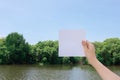 Woman hand holding white paper against mangrove forest and river with blue sky and cloud background Royalty Free Stock Photo