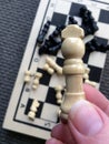 Woman hand holding a White queen piece over a chess board game Royalty Free Stock Photo