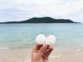 Woman hand holding white sea shell over seascape background. Relax in tropical sea concept.
