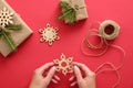 Woman hand holding wooden handmade snowflake over Christmas background with presents wrapped kraft paper and fir branches, twine, Royalty Free Stock Photo