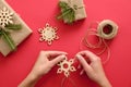 Woman hand holding wooden handmade snowflake over Christmas background with presents wrapped kraft paper and fir branches, twine, Royalty Free Stock Photo