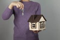 Woman hand holding wooden house model on gray background, Royalty Free Stock Photo