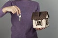 Woman hand holding wooden house model on gray background. Royalty Free Stock Photo