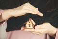 Woman hand holding wooden house model on gray background, Royalty Free Stock Photo