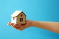 woman hand holding wooden model of house on blue background, Mortgage concept by house in hand, real estate insurance concept. Royalty Free Stock Photo