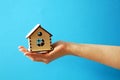 woman hand holding wooden model of house on blue background, Mortgage concept by house in hand, real estate insurance concept. Royalty Free Stock Photo