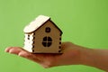 woman hand holding wooden model of house ongreen background, Mortgage concept by house in hand, real estate insurance concept.