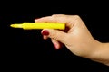 Woman hand holding yellow highlighter on the black background Royalty Free Stock Photo