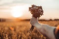 Woman hand holds a bouquet of wildflowers against a sunset background Royalty Free Stock Photo