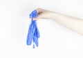 Woman hand holds a pair medical blue gloves against viruses and bacteria on a white background. Copy space