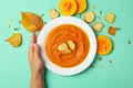 Woman hand holds plate of pumpkin soup