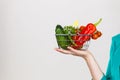 Woman hand holds shopping basket with vegetables Royalty Free Stock Photo