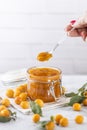 Woman hand holds spoon with homemade DIY natural canned yellow cherry plum sauce chutney with chilli or tkemali over glass jar Royalty Free Stock Photo