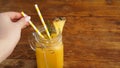 Woman Hand holds a straw, a glass of fresh pineapple juice, close up Royalty Free Stock Photo