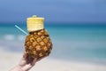 Woman hand holds tropical pineapple cocktail on the beach. Beautiful sea ocean sky white sand beach. Cuba space for text Royalty Free Stock Photo