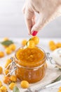 Woman hand holds yellow cherry plum over glass jar of homemade DIY natural canned yellow cherry plum sauce chutney with chilli or Royalty Free Stock Photo